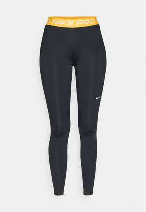 Fekete, sima textúrájú sportleggings, széles sárga derékrésszel, amelyen a "NIKE PRO" felirat található, valamint egy kicsi fehér Nike logó az oldalon.