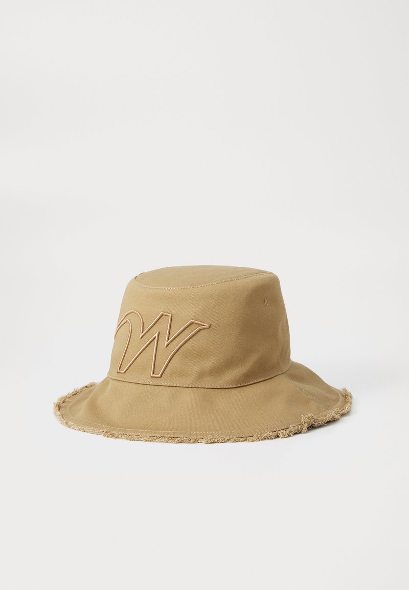 Beige Bucket Hat aus weichem Stoff, mit einem ausgefransten Rand und einem gestickten Logo in kontrastierendem Tan auf der Vorderseite.