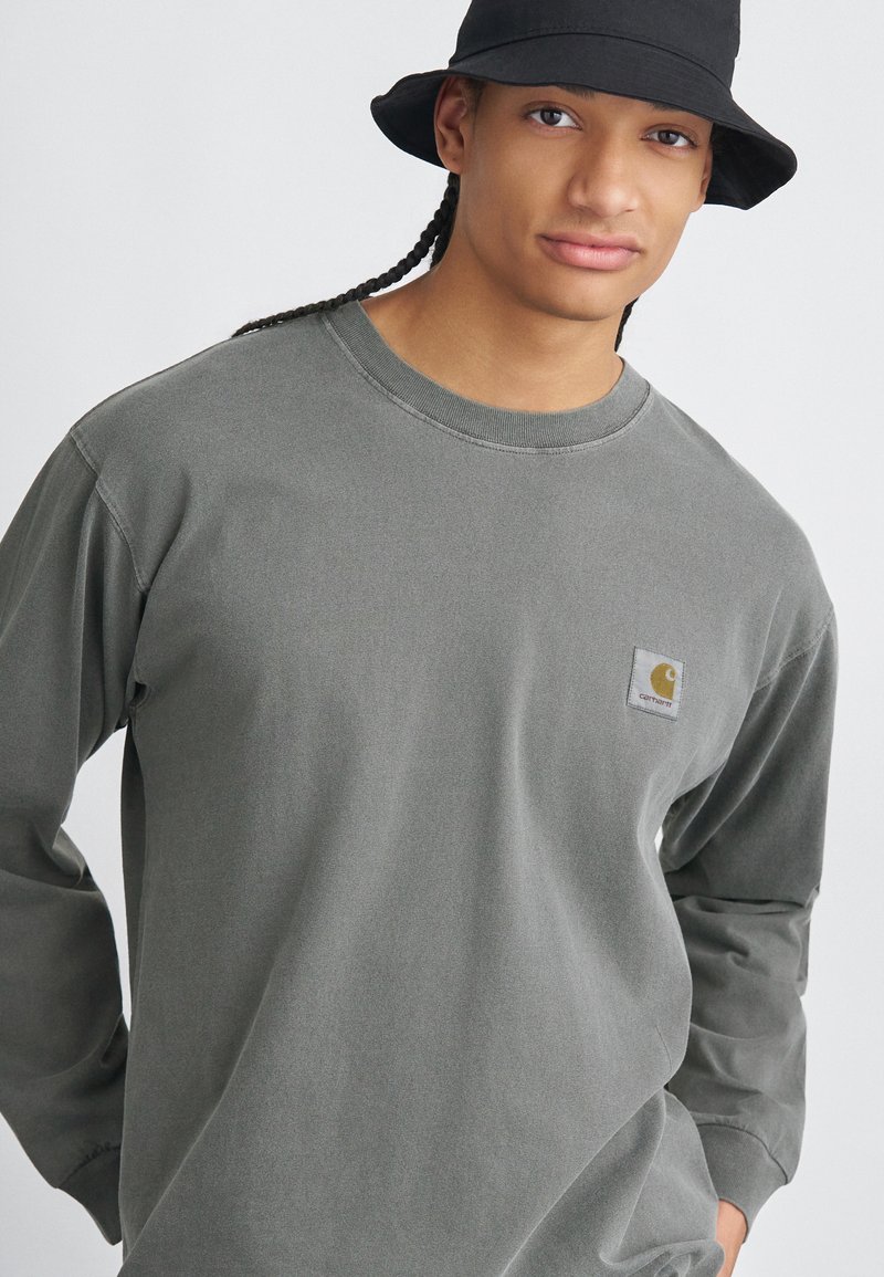 Grijze katoenen t-shirt met lange mouwen, een ronde hals en een klein logo op de linkerborst. De stof heeft een zachte textuur.