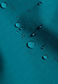 Aqua stof met een gepatternde structuur in een raster, met waterdruppels van verschillende groottes op het oppervlakte, die licht weerkaatsen.