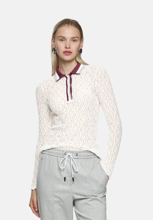 Weißes Spitzen-Poloshirt mit langen Ärmeln und burgunderrotem Kragen. Es verfügt über einen strukturierten Stoff und einen knöpfbaren Ausschnitt, kombiniert mit hellgrauer Hose.