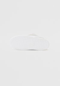 Fehér sneaker talp, érdes tapintású mintázattal, lapos formával és sima élekkel. Megerősített gumi anyag; minimalista dizájn díszítések nélkül.