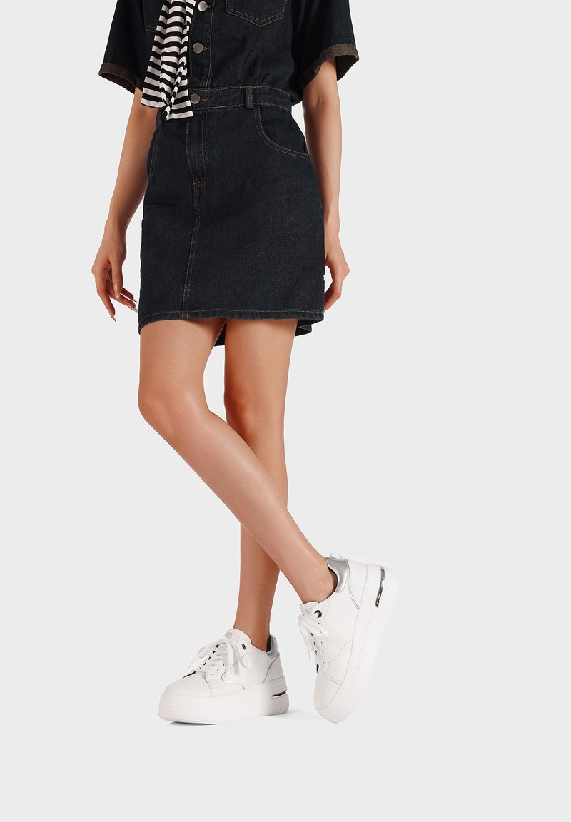 Sneakers platform bianchi con accenti argento, dotate di lacci e un design elegante. Indossati con una gonna di jeans e una maglietta a righe per il contrasto.