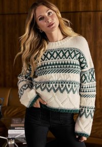 Pulover tricotat cu o bază crem și modele geometrice verzi. Are un guler rotund și manșete texturate. Croi scurt cu accente decorative.