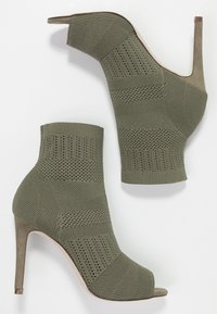 Bottines en tricot vertes à bout ouvert, avec des talons aiguilles hauts et une texture côtelée. Présentent un talon en daim contrastant et un tissu élastique pour un ajustement parfait.