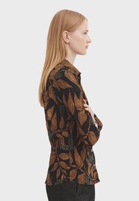 Black shirt with orange and green leaf patterns, button-down design, long sleeves, and a fitted cut, shown from the side.