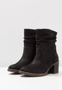Botas negras hasta el tobillo hechas de suave ante, con un diseño arrugado, puntera redondeada y un tacón bloque de altura media con un acabado texturizado.