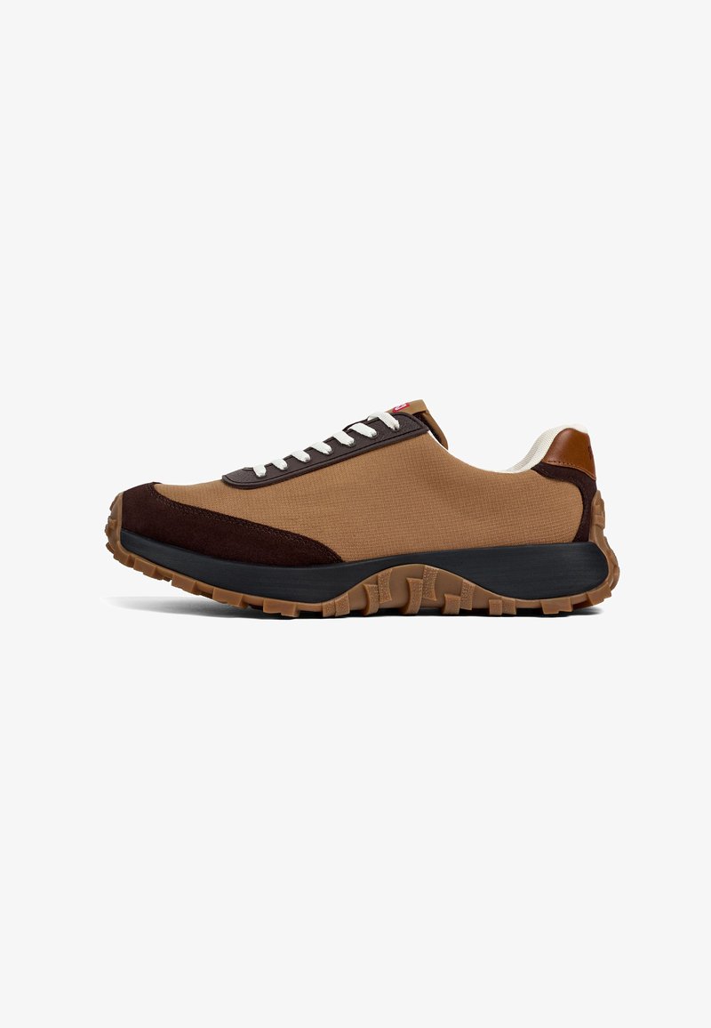 Tan sneaker with dark brown accents, a textured canvas upper, contrasting laces, and a rugged rubber sole featuring deep treads for traction.