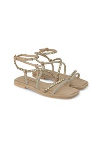 Sandali piatti beige con fasce incrociate, decorati con dettagli metallici e perline, con una soletta testurizzata e una suola bassa.