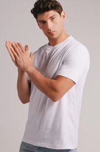 Bílý krátký rukáv tričko vyrobené z bavlny, s kulatým výstřihem, volným střihem a hladkou texturou. Model pózuje s rukama složenýma.