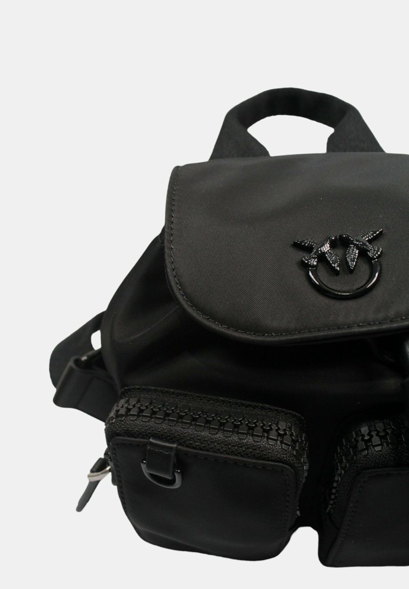 Schwarzer Stoff-Rucksack mit Klappenverschluss, zwei vorderen Reißverschlusstaschen mit strukturierten Akzenten und einem oberen Tragegriff.