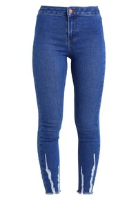 Jeans ajustados de mezclilla azul, con detalles desgastados, dobladillos deshilachados en los tobillos y un diseño clásico de cinco bolsillos.