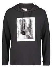 Černá bavlněná mikina s dlouhými rukávy, kapucí na šňůrku, přední grafický potisk zobrazující model a nápis pod obrázkem.