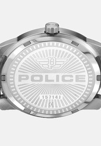 Hõbedane roostevabast terasest kell ringikujulise korpusega, millel on radiaalne muster ja graveeritud "POLICE" logo metallkellapäeval.