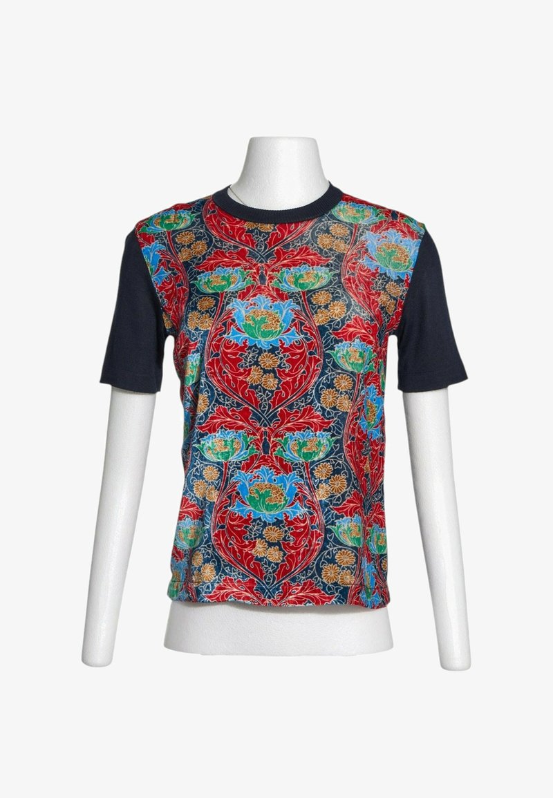 T-shirt à manches courtes avec manches noires et un panneau avant présentant un motif floral et de feuilles coloré en rouge, bleu, vert et jaune.