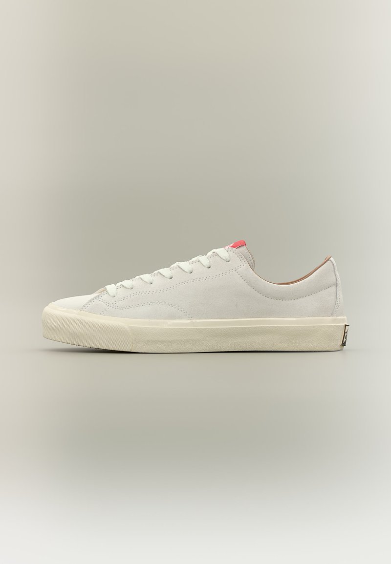 Baskets basses en daim blanc avec lacets blancs, semelle beige et un petit accent rouge sur le col du talon, vues de profil.