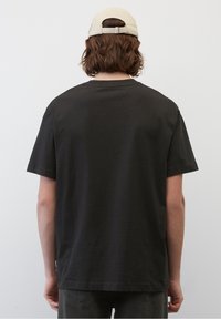 Mørkegrå bomulds t-shirt med korte ærmer, rund hals og en afslappet pasform. Bagfra er designet ensfarvet, uden synlige mønstre eller accenter.