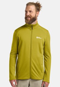 Veste en polaire verte avec un col montant, fermeture �éclair intégrale et logo sur la poitrine. Comprend un tissu texturé et des poches latérales.