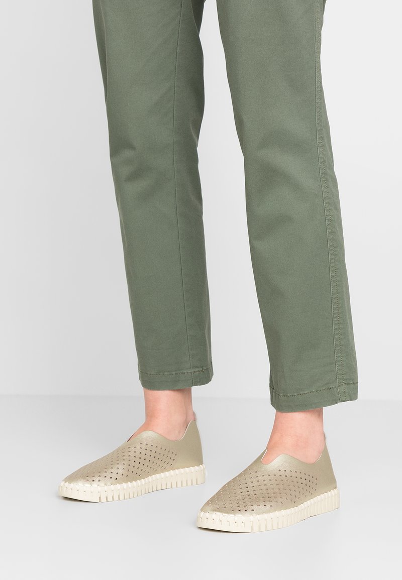 Zapatos de color verde claro tipo slip-on con un upper perforado, suela de goma blanca contrastante con dibujo visible y una textura suave.
