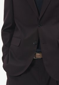 Blazer mov închis cu două nasturi, buzunare laterale și o textură subtilă. Un curea maro este vizibilă, purtată peste pantaloni negri.