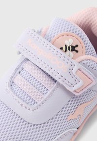 Ανοιχτό μοβ αθλητικό παπούτσι KangaROOS με ύφασμα από δίχτυ και λουράκι με βέλκρο, διακοσμημένο με ροζ έμβλημα μέλισσας και υφασμένα διακοσμητικά στοιχεία.