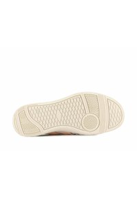 Podešev tenisky vyrobená z texturovaného gumového materiálu ve světle béžové barvě, se vzorem rybí kosti a kruhovým akcentem poblíž paty.
