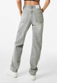 Gray denim jeans with a relaxed fit, featuring two back pockets and a high waist. The material has a slightly textured finish.