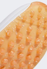 Rubberen schoenzool, oranje met zeshoekige noppen, geprofileerd oppervlak, witte zijkantdetails. Zichtbare vuilresten op het oppervlak van de zool.