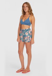 Soutien-gorge de bikini triangulaire bleu avec des bretelles fines, accompagné de shorts floraux teal ornés d'accents roses et oranges. Le mannequin porte des tongs roses.