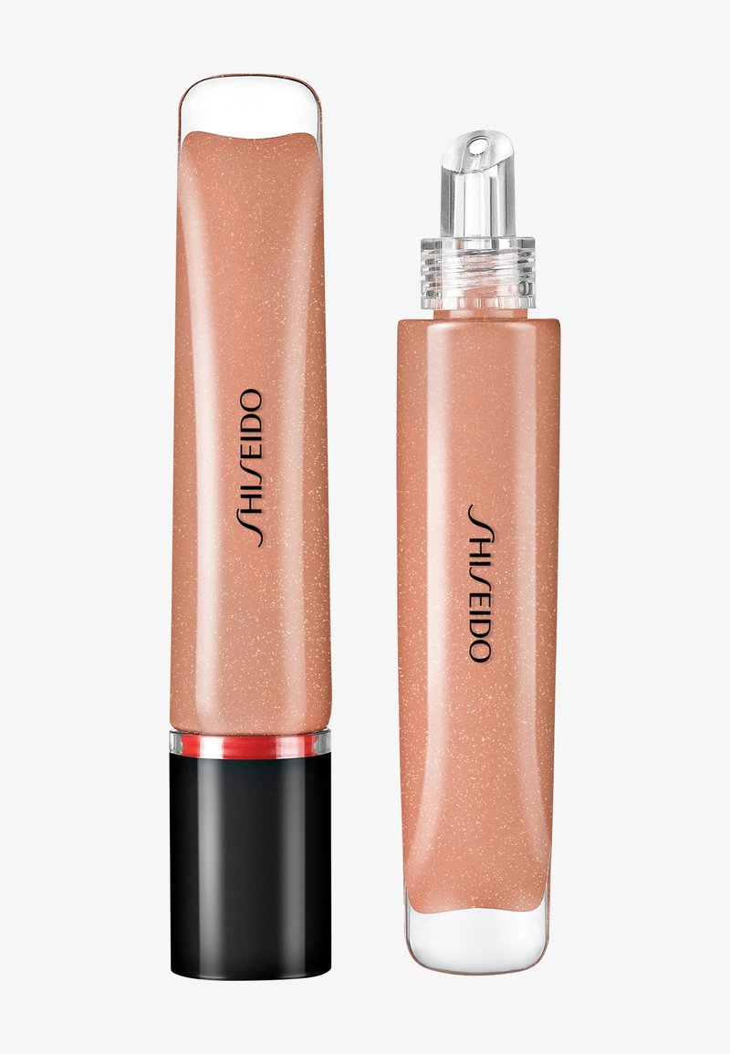 Two Shiseido lip gloss tubes in shimmery nude beige, one with black cap and one with clear, angled applicator tip.