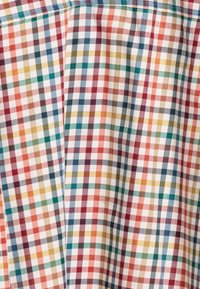 Gingham stof met een multicolore patroon van rode, groene, blauwe en gele vierkanten op een witte achtergrond, met een gladde textuur.