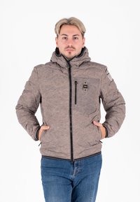 Giacca trapuntata marrone con cappuccio, chiusura con zip e tasche frontali. Presenta una tasca sul petto con un logo sulla manica.