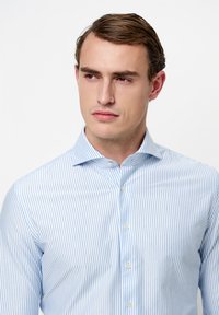 Gestreept overhemd met knopen in lichtblauw en wit, voorzien van een klassieke kraag, lange mouwen en een getailleerde pasvorm met een subtiele textuur.