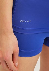 Niebieskie sportowe spodenki Dri-FIT z gładkiej, teksturowanej tkaniny. Charakteryzują się dopasowanym krojem i kontrastującymi szwami.