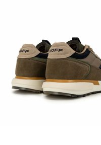Sneaker con tomaia in suede e mesh nelle tonalità di verde e beige. Presenta un tab sul tallone nero e una suola bianca e marrone. Logo del marchio sul tallone.