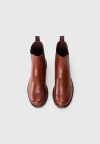Bottines en cuir marron avec une finition lisse, des panneaux latéraux élastiques et des tirettes en boucle, dotées d'une semelle en caoutchouc noir robuste.
