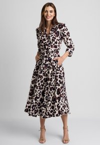 Sukienka w kolorze kremowym z ciemnobrązowym i czarnym wzorem zwierzęcym. Długie rękawy, kieszenie i wiązany pas podkreślają sylwetkę w kształcie litery A.