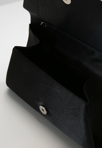 Pochette rettangolare nera con pattina ripiegata e bottone a scatto argento, mostrata aperta con interno vuoto.