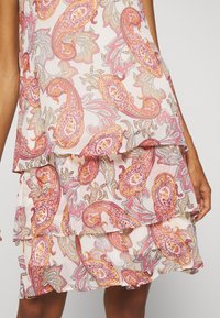 Rosa paisley-mønstrede kjole med lagdelte flæser. Lavet af letvægtsstof, med intrikate blomsterdesigns i orange og grå nuancer.