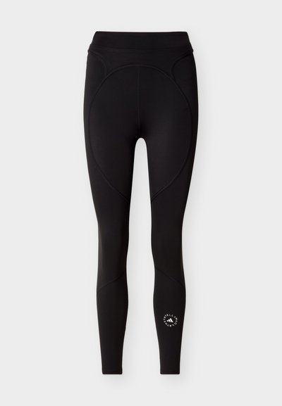 Μαύρο αθλητικό κολάν με ψηλή μέση, διακοσμητικές ραφές με καμπύλες και κυκλικό λευκό λογότυπο κοντά στο κάτω μέρος του δεξιού ποδιού.