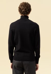 Schwarzer Rollkragenpullover aus weichem Strickmaterial mit gerippten Bündchen und Saum. Entworfen mit einer körpernahen Silhouette und ohne sichtbare Verzierungen.
