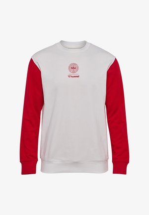 Biała bluza z okrągłym dekoltem z czerwonymi długimi rękawami, z logo Duńskiej Federacji Piłkarskiej i nazwą marki Hummel w czerwonym kolorze na piersi.