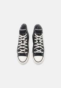 Black high-top sneakers with white laces, rubber soles, and contrasting white toe caps. Inner lining features a leopard print pattern.