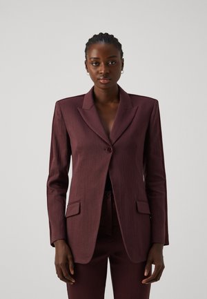 Blazer burdeos con solapas de muesca, cierre de un solo botón y dos bolsillos frontales. Tejido texturizado con un corte ajustado, combinado con pantalones a juego.