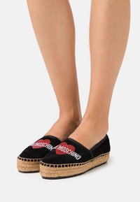 Svarta mocka espadrillos med röd och silver "Moschino" logga med hjärtdesign, flätad halmsula och platt slip-on stil.