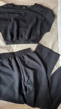 Top negro recortado con dobladillo elástico, combinado con pantalones negros a juego con una cinturilla elástica y un patrón de tejido texturizado.