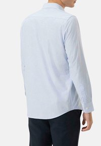 Camisa de manga larga a cuadros azul y blanca con textura suave, cuello abotonado y puños ajustables, que presenta un dobladillo curvado.