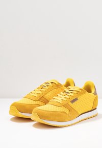Gelbe Sneakers aus einer Mischung von Mesh- und Wildledermaterialien, mit runder Zehenpartie und strukturierten Akzenten. Mit Schnürverschluss und weißer Sohle.