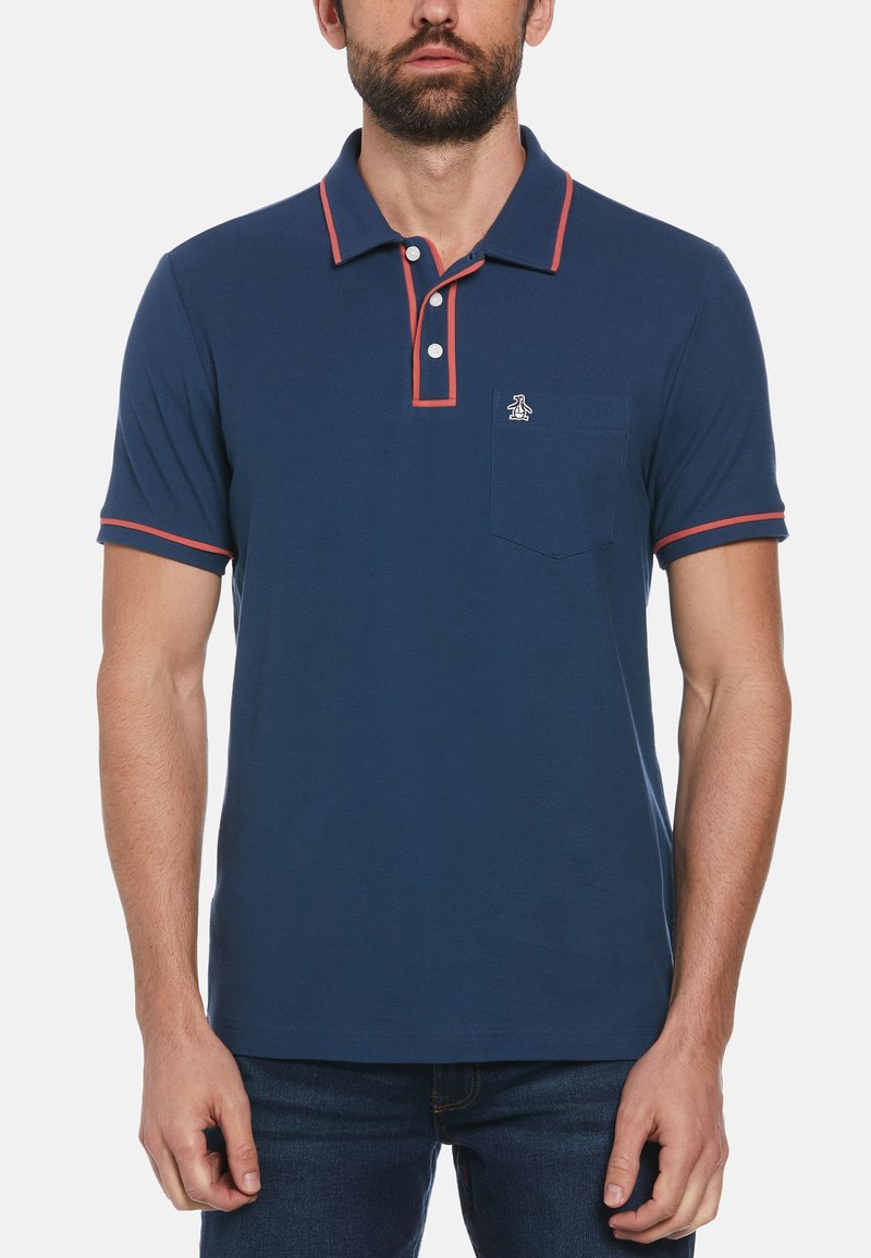 Polo shirt marine en coton, avec un col et une patte de boutonnage à trois boutons. Présente des finitions rouges contrastantes sur les manches et le col, ainsi qu'une poche poitrine.