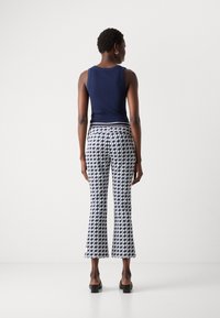 Marineblauw geribbelde tanktop gecombineerd met gebloemde flared broek in marineblauw en wit. De broek heeft een houndstooth ontwerp en zijstukken.